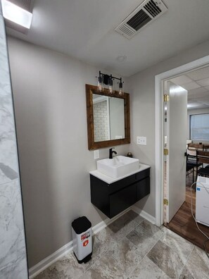 Een badkamer met een wit wastafelblad, een zwart aanrecht en een spiegel met houten lijst.