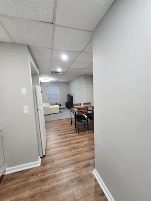 A hallway with a dining area, a white couch, and a television. - The Quiet Studio, lux apartment, in central area. (Newnan)