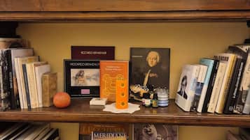 A bookshelf with books, a small orange object, and a decorative item.
