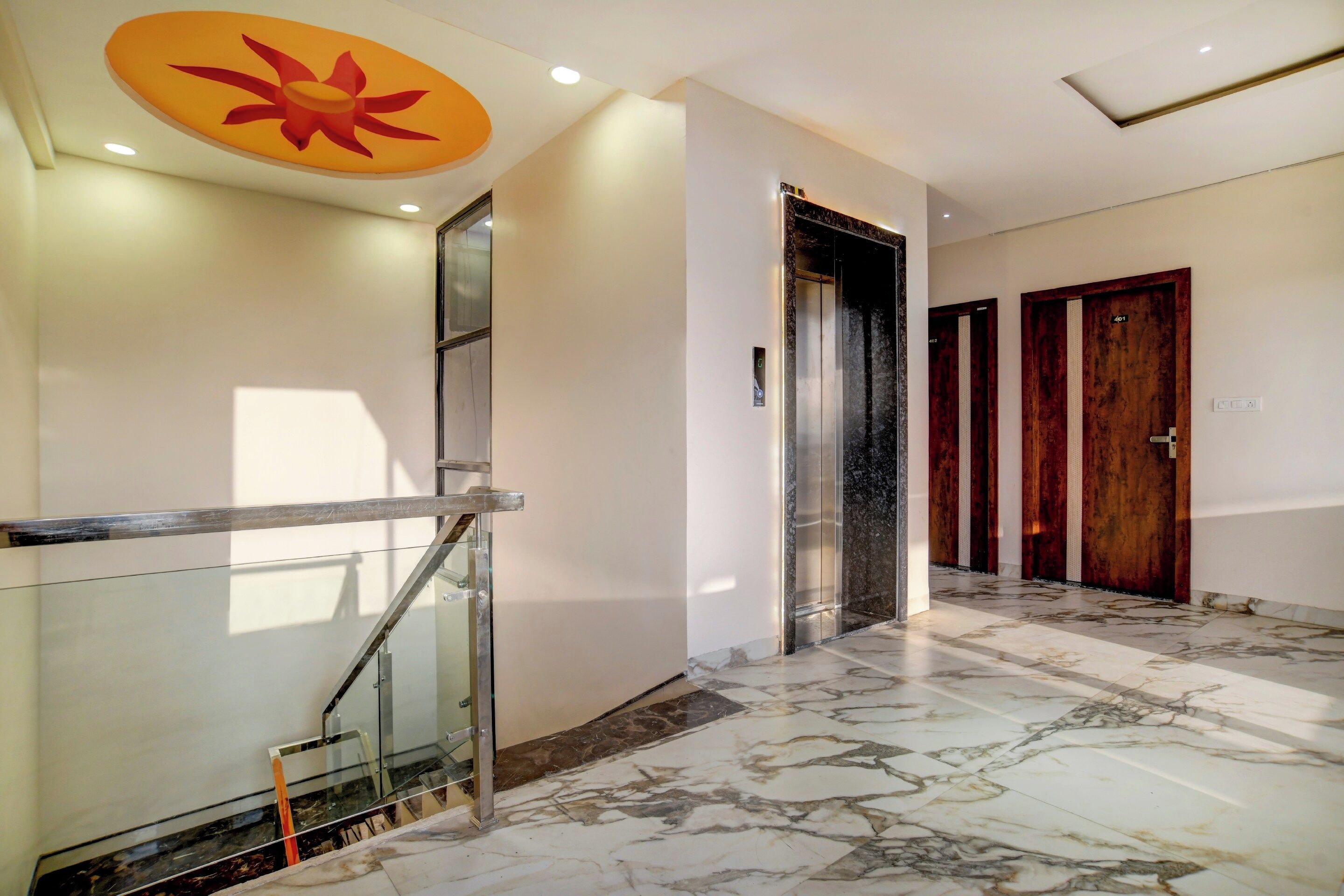 Un interior moderno con piso de mármol, escalera de cristal y puerta de madera.