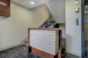 Zona de recepción con suelo de mármol, una escalera y un refrigerador Samsung.