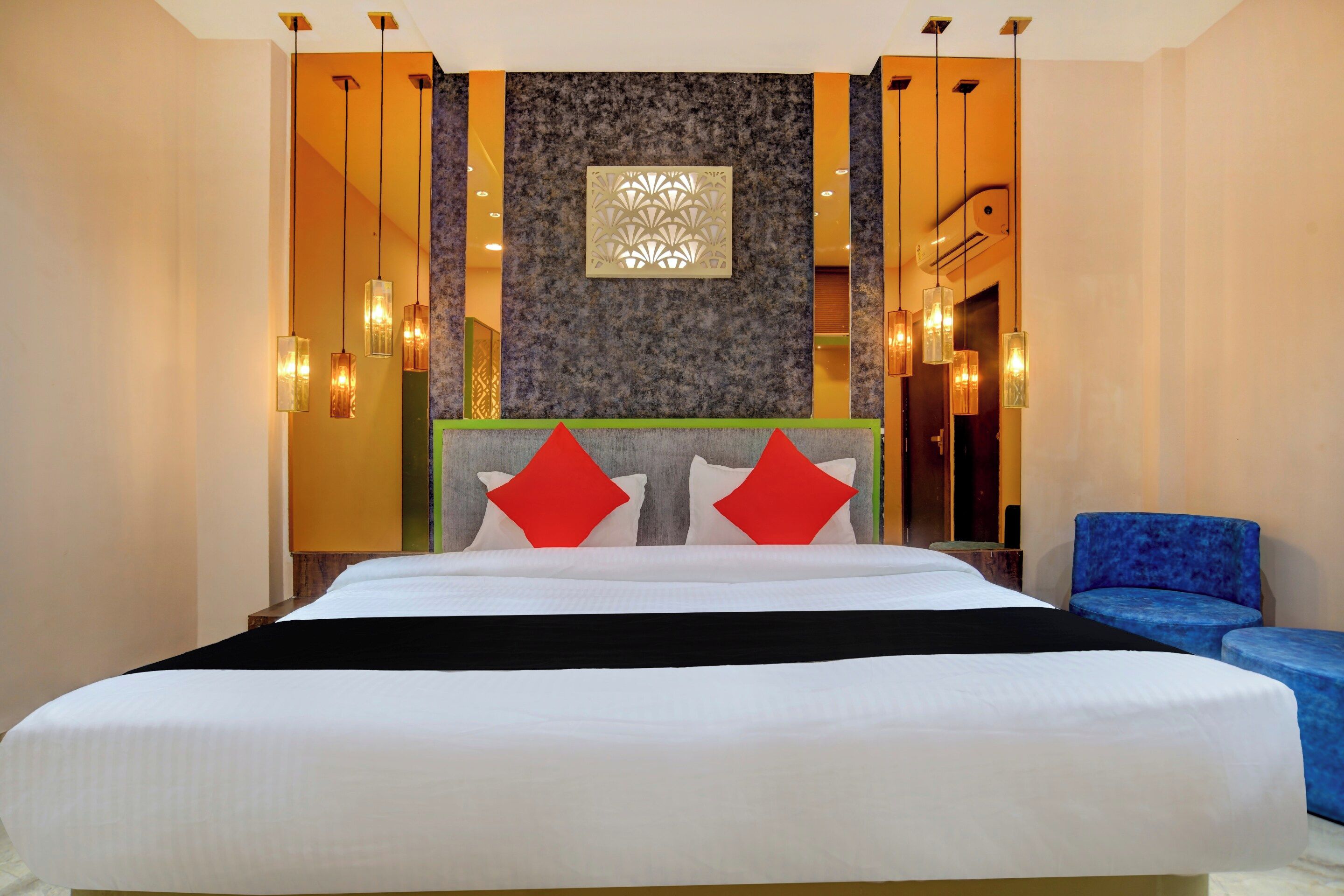 Una habitación de hotel con una cama grande, un sillón azul y un panel decorativo en la pared.