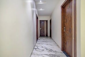 Un pasillo con piso de mármol, puertas de madera e iluminación empotrada en el techo.
