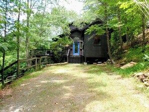A wooden cabin with a blue door, surrounded by a forested area with a gravel path leading to it. - Hawk's View Chalet
with add on Bunkie Rental (Murphy)