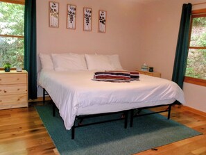 A bedroom with a bed, a dresser, and a window with curtains. - Hawk's View Chalet
with add on Bunkie Rental (Murphy)