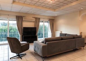 Ein modernes Wohnzimmer mit einer Couch, einem Sessel und einem Flachbildfernseher.