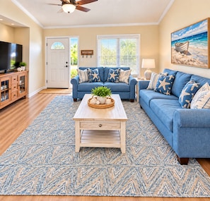 A living room with a blue sofa, a coffee table, and a television. - Palm Coast canal home / Pool / Spa & Boat Dock with beautiful sunsets! (Palm Coast)