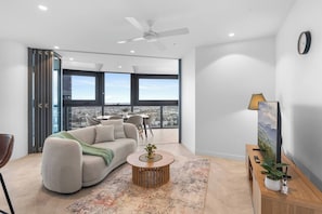 A modern living room with a sofa, coffee table, and a city view through large windows. - Elegant High-Floor 3BR with Skyline Views (Brisbane City)