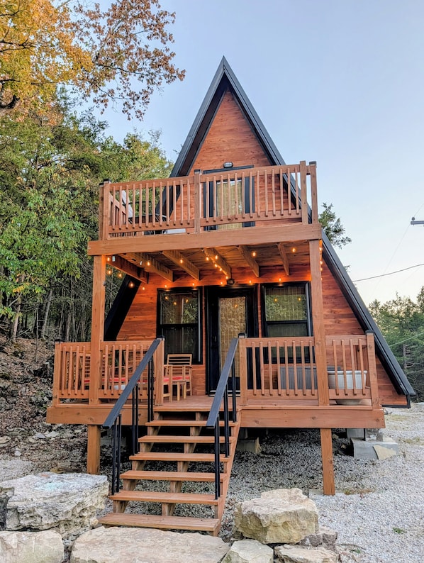 Eine Holzhütte mit Balkon, Treppe und Lichterkette.