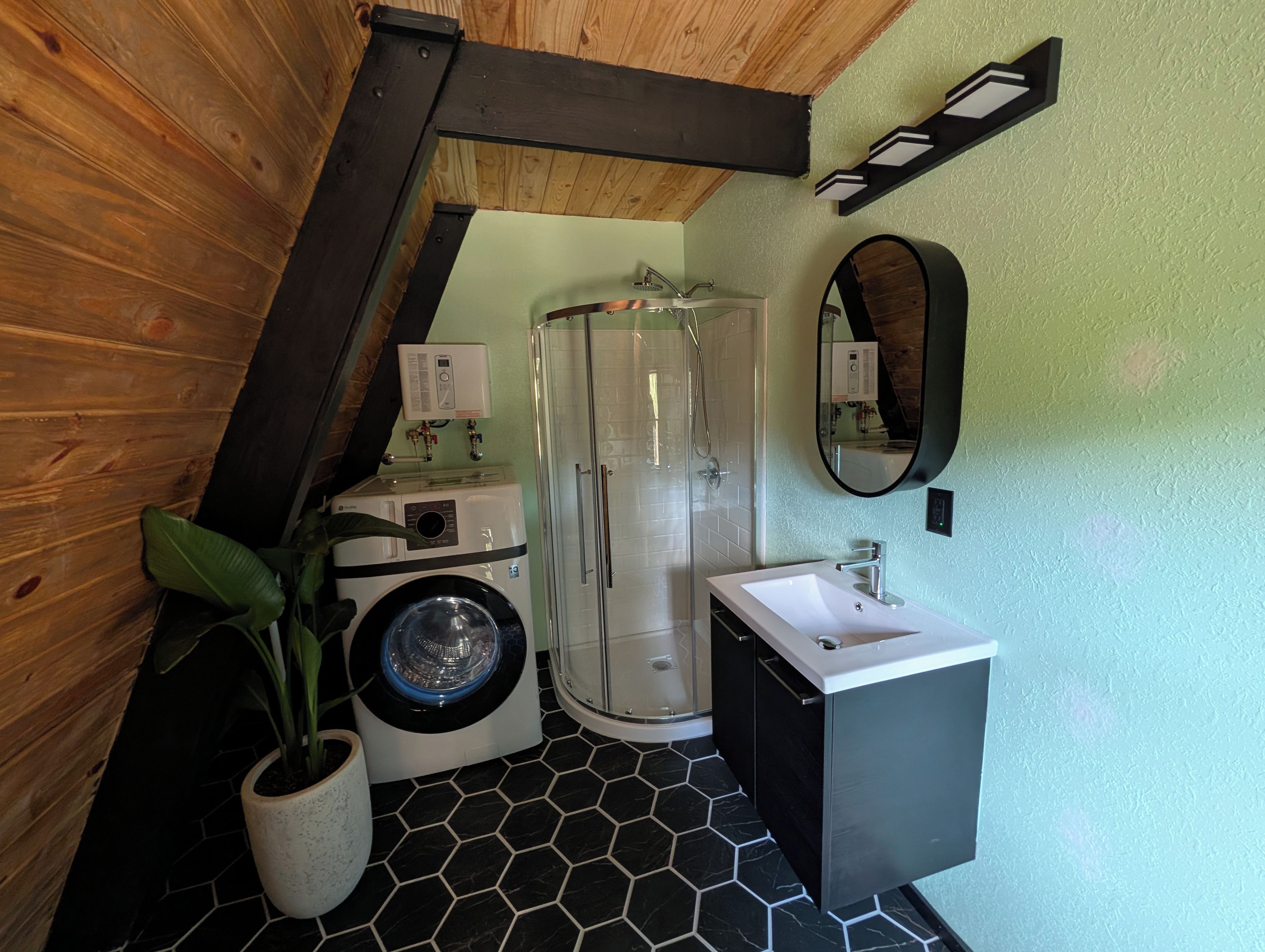 A compact bathroom with a washing machine, a shower enclosure, and a sink.
