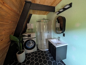 A compact bathroom with a washing machine, a shower enclosure, and a sink. - Entire chalet in Branson, Missouri (Branson)