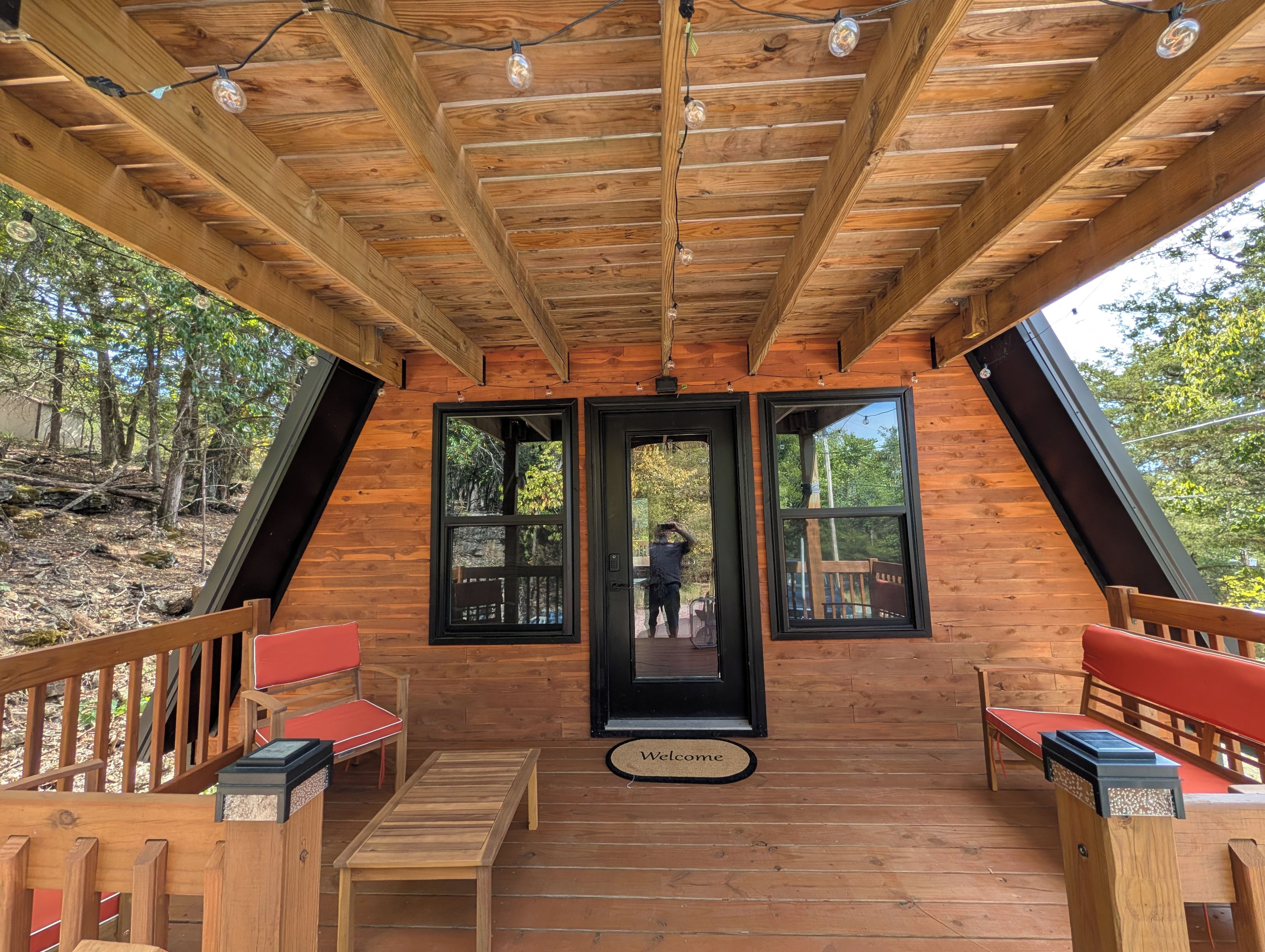 Eine Holzterrasse mit einer Bank, einem Tisch und einer Tür zu einem überdachten Bereich.