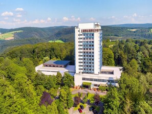 Ein hoch aufragendes Hotel im modernen Stil, umgeben von üppiger Vegetation und Hügeln.