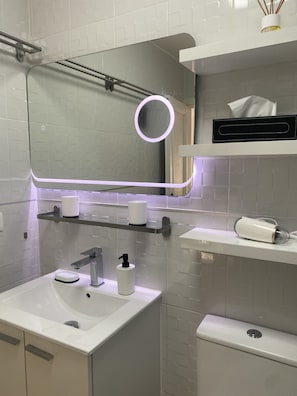 Une salle de bain moderne avec un lavabo blanc, un miroir et un porte-serviettes.