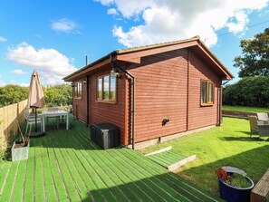 A wooden cabin with a deck, a table, and an umbrella. - Elsie Lodge (Hastings)