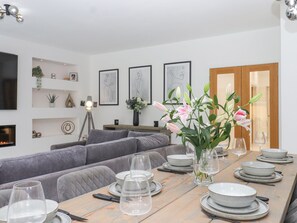 Ein modernes Wohnzimmer mit einer Couch, einem Esstisch für vier Personen und einem Kamin.