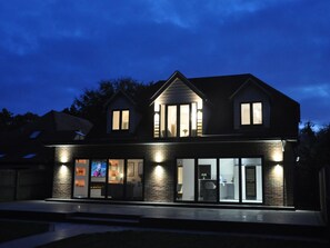 Ein zweistöckiges Haus mit Backsteinfassade, großen Fenstern und einer gut beleuchteten Außenansicht.