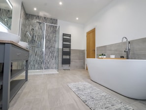 Un baño moderno con una bañera independiente, ducha con mampara de vidrio y tocador con lavabo.