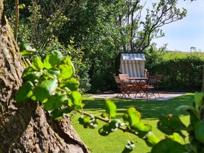 A patio area with outdoor furniture, a covered seating area, and a tree in the foreground. - Holiday Apartment Ankerplatz Wrixum (Wrixum)
