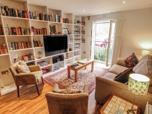 A living room with a television, bookshelves, two sofas, a coffee table, and a patterned rug. - Apartment 173 (Lincoln)