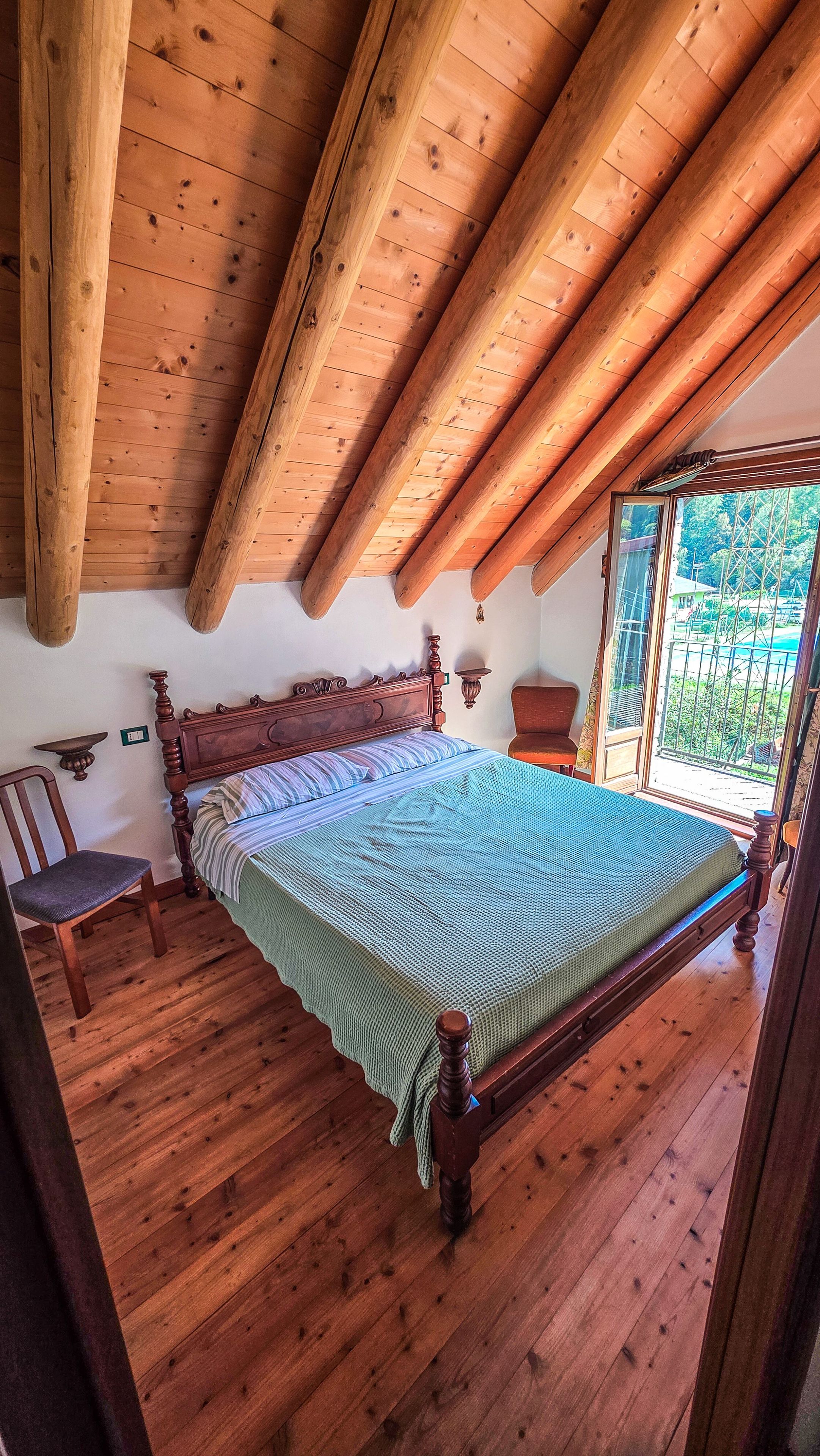 Une pièce en bois avec un lit, une chaise et une fenêtre.