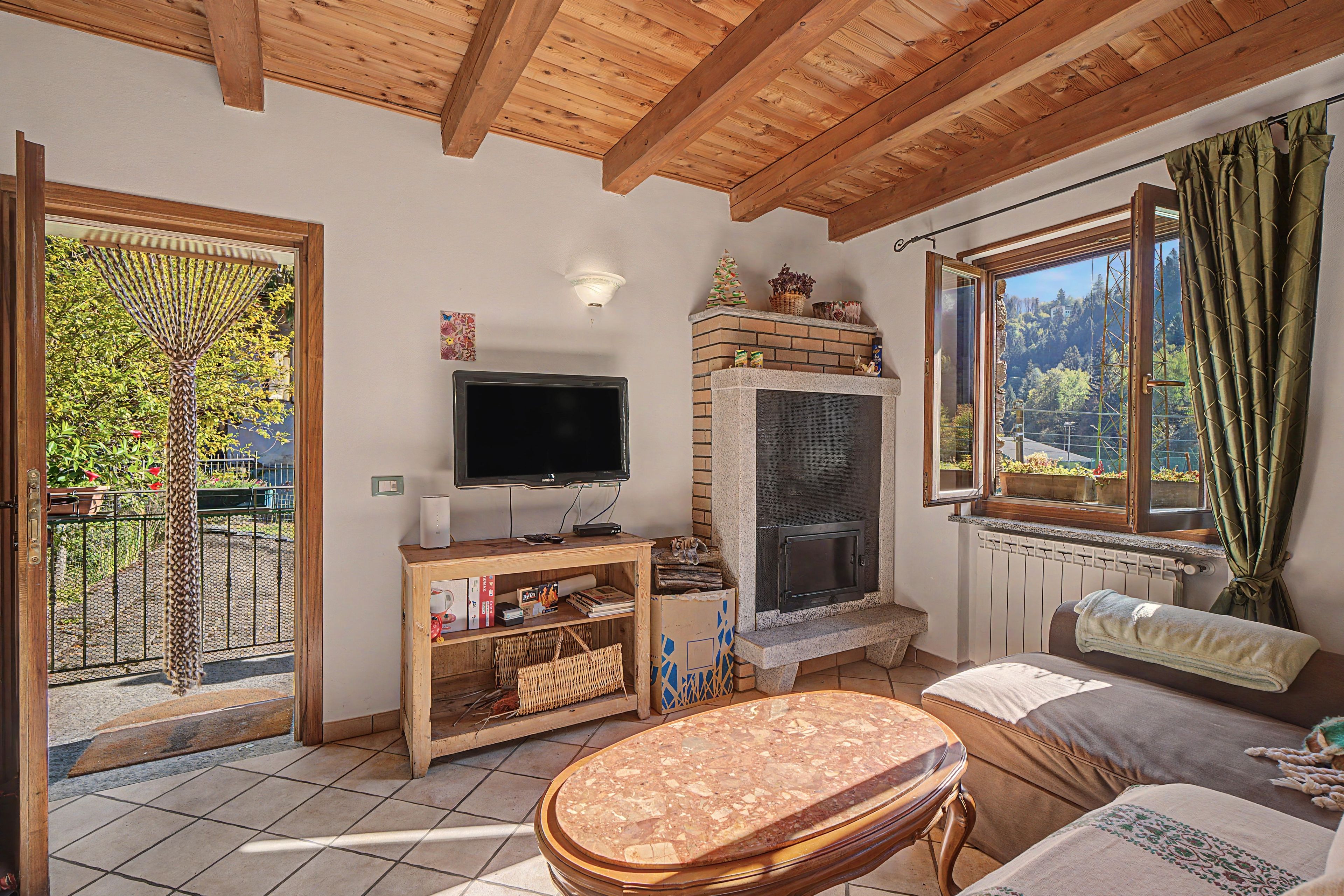 Una sala de estar acogedora con televisor, chimenea y vistas al exterior.