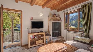 Una sala de estar acogedora con televisor, chimenea y vistas al exterior.