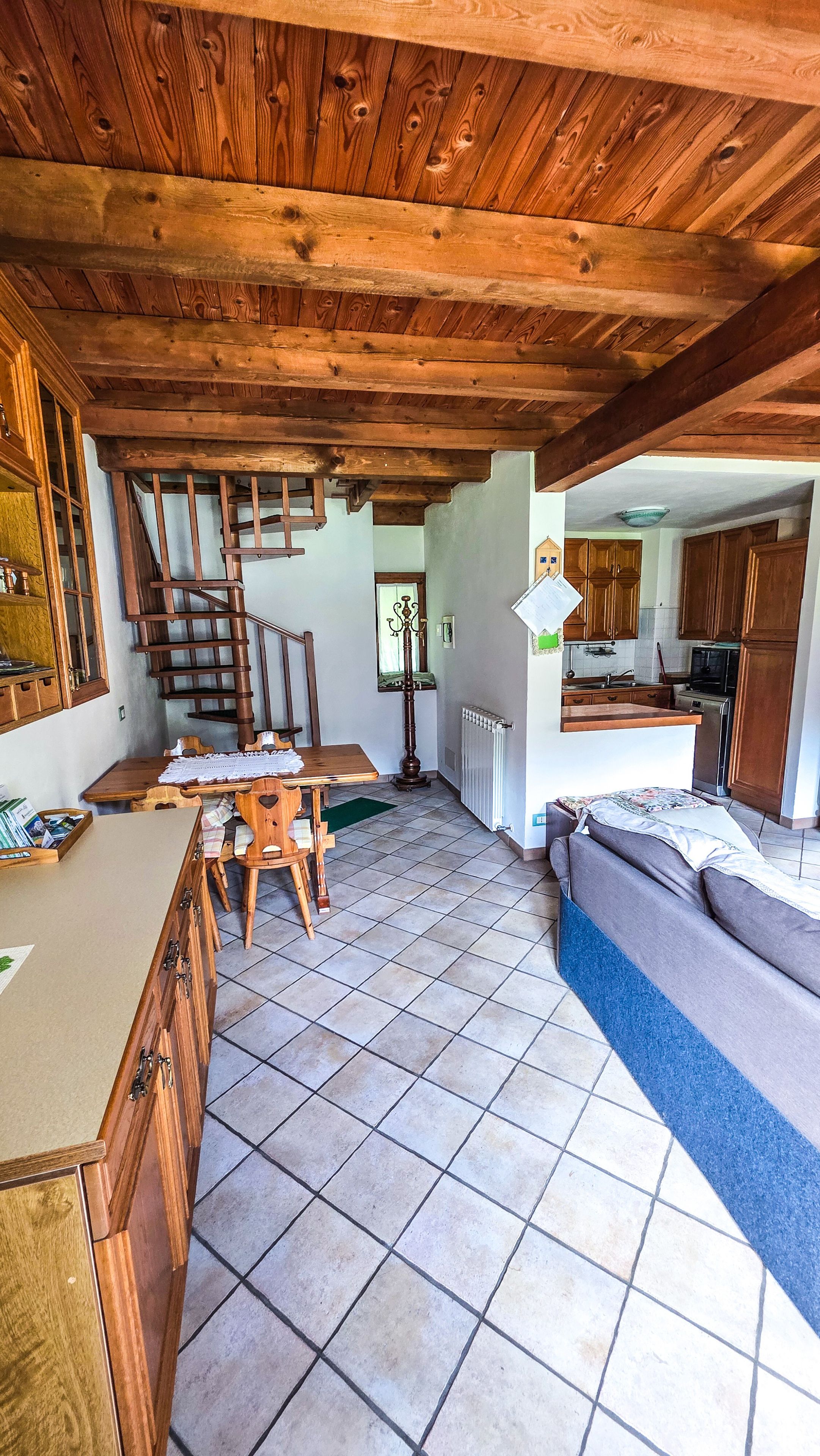 A spacious living area with a wooden staircase, a dining table, and a kitchen area.