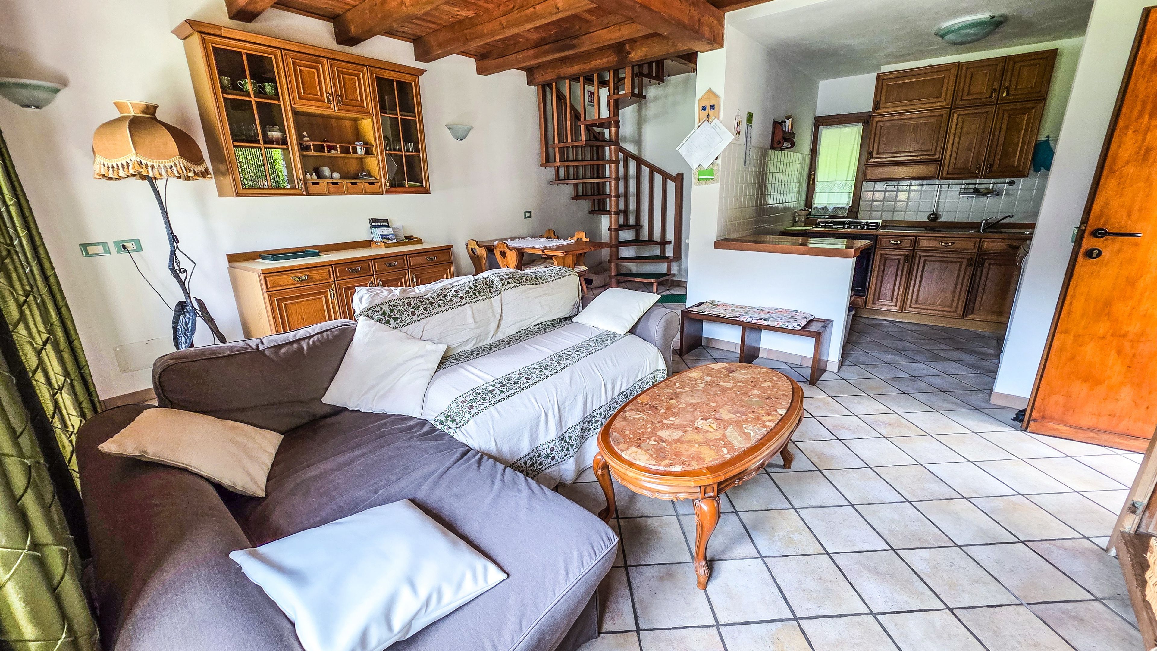 Ein gemütliches Wohnzimmer mit einer Couch, einem kleinen Tisch und einer Treppe, die zu einer Küchenzeile führt.