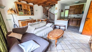 Una sala de estar acogedora con un sofá, una mesita y una escalera que lleva a una zona de cocina.
