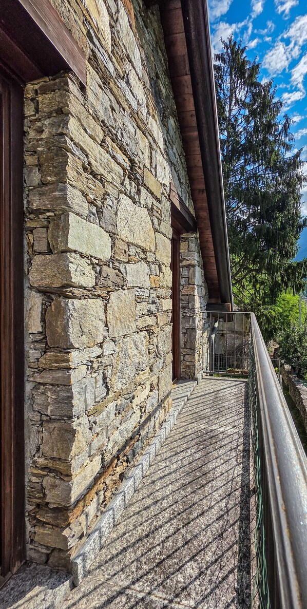 Ein Steinhaus mit einer Holztreppe, die zu einem Balkon führt.