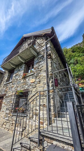 Ein Steinhaus mit Balkon und einer Treppe, die hinauf führt.