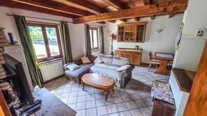 Ein gemütliches Wohnzimmer mit einer Sofagarnitur, einem Holztisch und einem Essbereich mit Schrank und Stühlen.