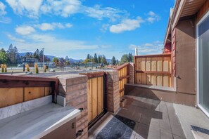 Eine Dachterrasse mit Blick auf eine gebirgige Landschaft, einem Holzzaun und einem Gebäude mit rotem Dach.