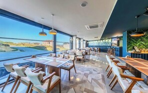 A modern dining area with large windows, a view of the landscape, and a variety of seating arrangements. - Heaven Prime Airport Hotel (Arnavutkoy, Turkiye)