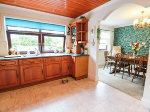 Une cuisine avec des meubles de rangement en bois, un évier et un coin repas comprenant une table et des chaises.