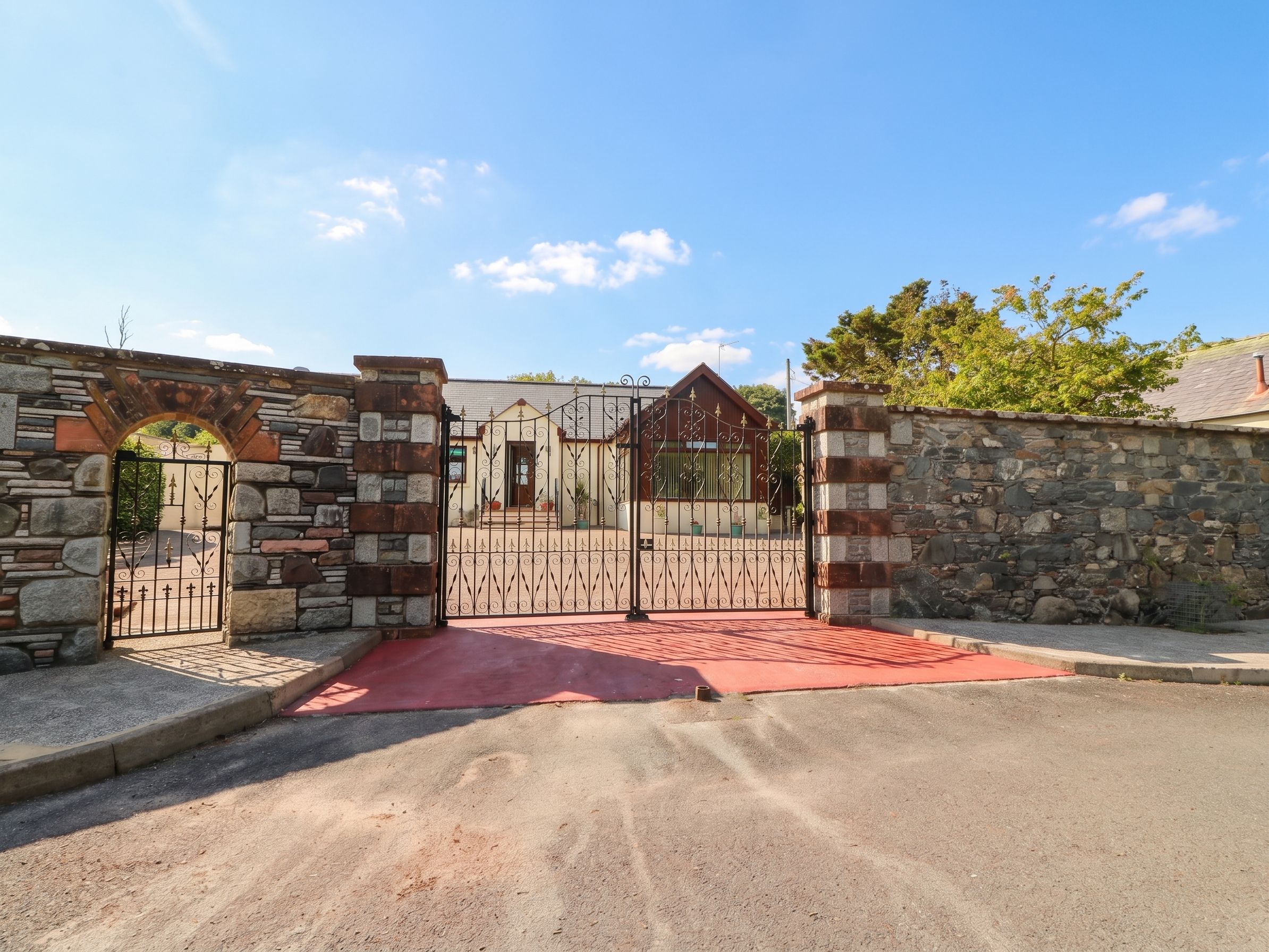 A gated entrance with stone walls and a metal gate.