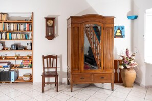 A room with a wooden cabinet, a bookshelf, a chair, and a vase with flowers. - A corner of paradise in Anacapri with a private sea-view sun terrace (Anacapri)