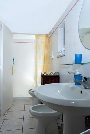 Ein Badezimmer mit einem weißen Waschbecken, einem Spiegel, einer Toilette und einer Duschkabine.