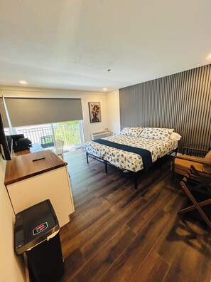 Een hotelkamer met een bed, een bureau, een stoel en een balkon met uitzicht.