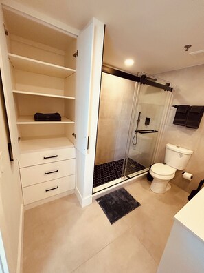 Een badkamer met een douche, toilet en een wit opbergmeubel met lades.