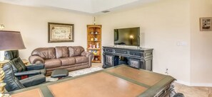 A living room with a leather sofa, a television, a cabinet, and a bookshelf. - Paradise Preserve (Rotonda West)