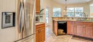 A kitchen with a stainless steel refrigerator, wooden cabinets, a built-in dishwasher, and a window providing natural light. - Paradise Preserve (Rotonda West)