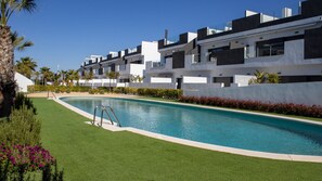 A modern residential building with a swimming pool, surrounded by well-maintained lawns and palm trees. - Alma Rosa - modern appartement met 80 m2 prive dakterras (Torrevieja)