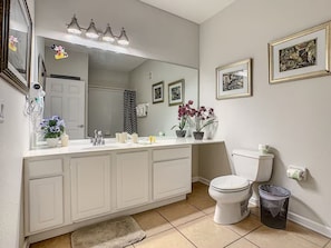 Ein Badezimmer mit weißem Waschtisch, Toilette, Mülleimer und beleuchtetem Spiegel.