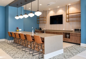 Una cocina moderna con una isla central, taburetes de bar, un televisor de pantalla plana y una alfombra estampada.