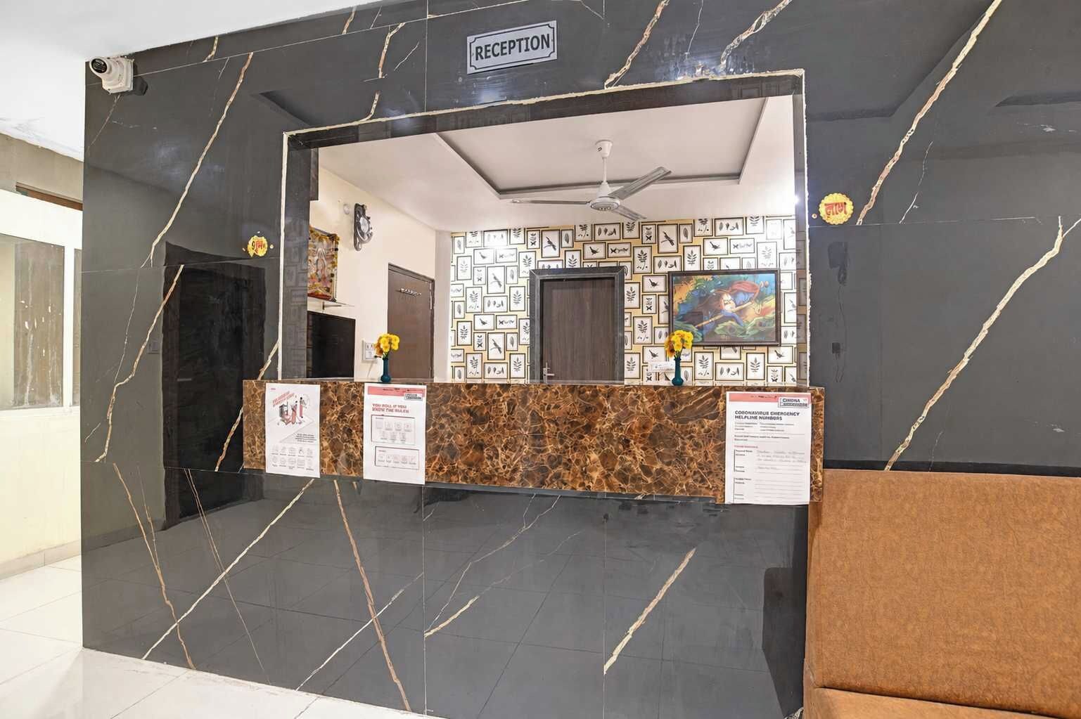 A reception area with a marble wall, a reception desk, framed artwork, and a ceiling fan.