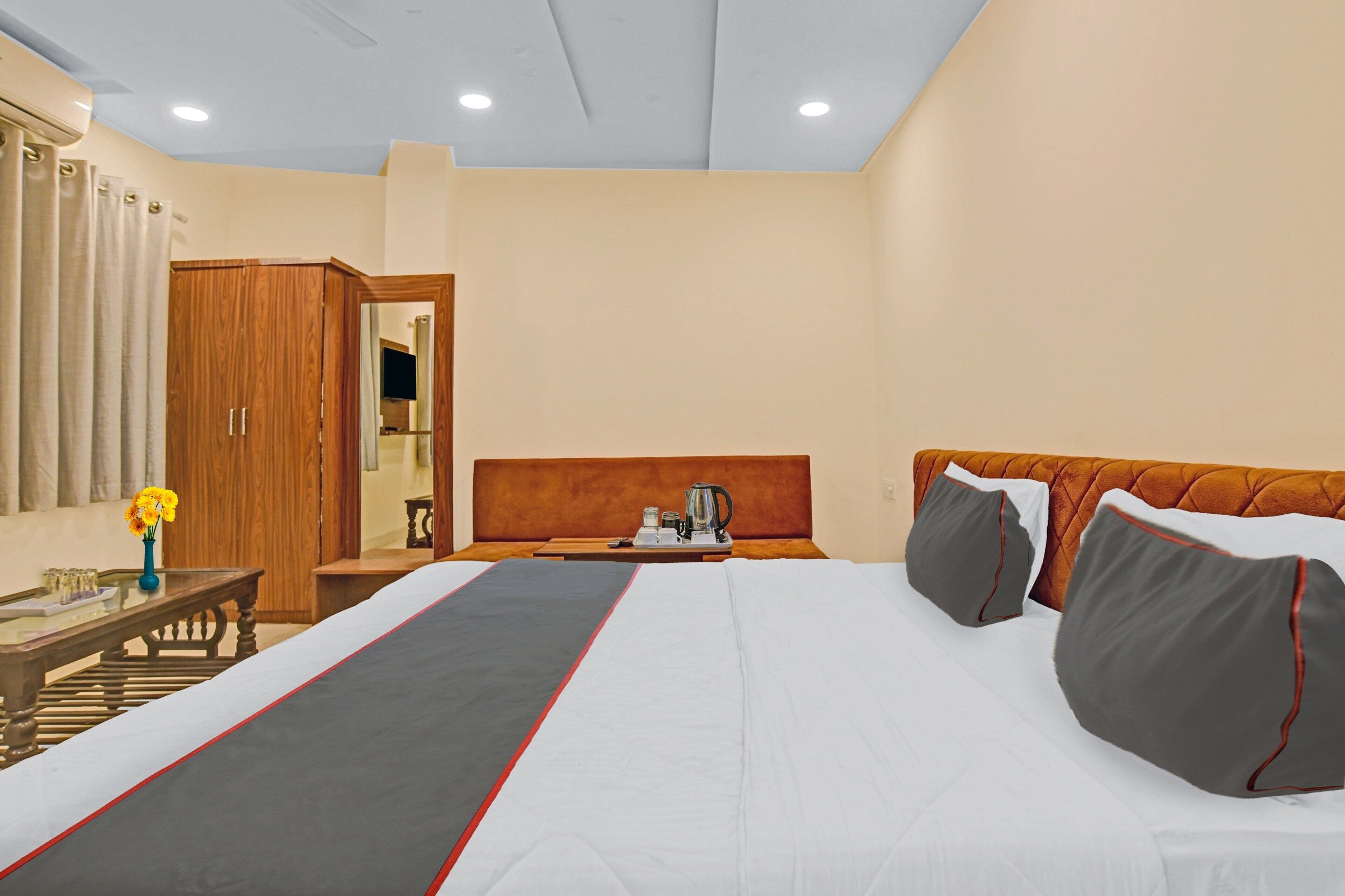 A hotel room with a bed, bedside table, and a mirror.