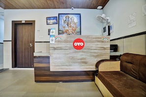 Una recepción con logotipo, detalles de madera, un sofá marrón y una puerta.