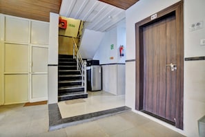 Un pasillo con una puerta de madera, una escalera y un extintor en la pared.